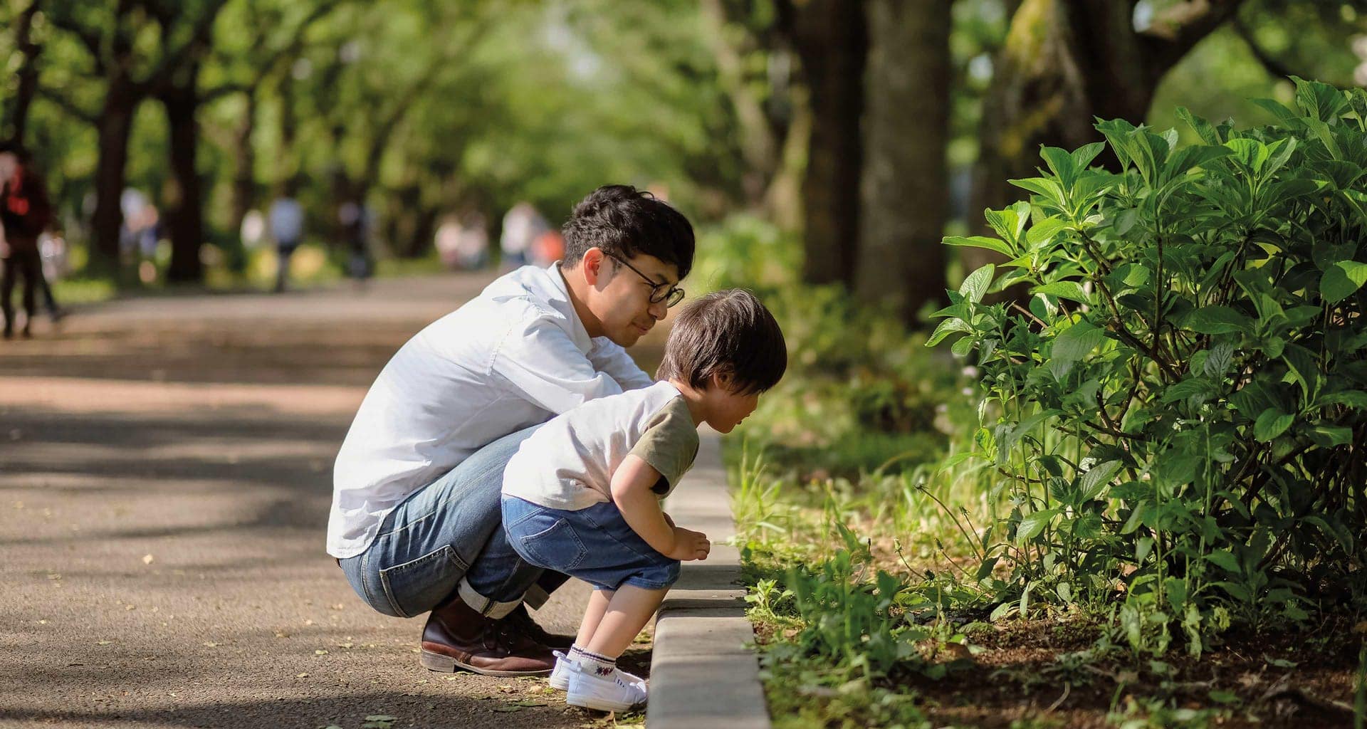 Father and son looking at plants in a park